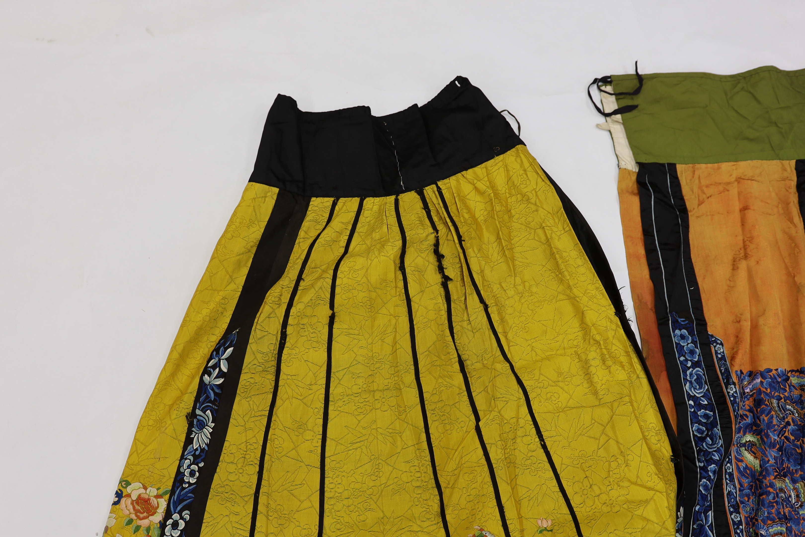 A late Chinese Qing yellow silk damask wedding skirt, with polychrome coloured silk embroidery, together with a similar coral silk damask blue embroidered wedding skirt